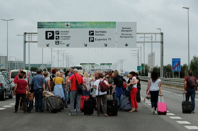 旅客拉着行李箱走在巴塞罗机场高速路上