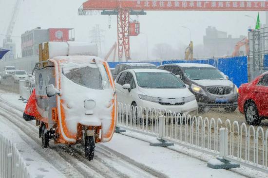  2020年2月14日，北京迎来降雪天气，快递小哥忙着送货。图 | 视觉中国